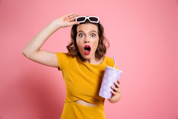 Portrait of a shocked girl in sunglasses holding cup Free Photo