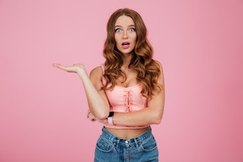 Portrait of a surprised pretty woman in summer clothes pointing Free Photo