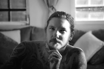 Portrait of a Tattooed Man Sitting Shirtless