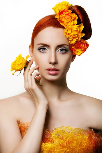 Portrait of beautiful woman with flowers, holding a yellow rose near the person
