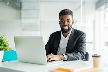 Portrait of handsome african black young business man working on laptop at office desk Free Photo
