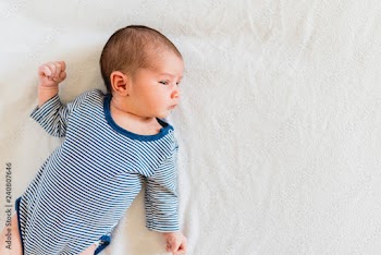Portrait of pretty newborn girl lying on her bed and looking at the camera.