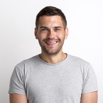 Portrait of smiling charming young man in grey t-shirt standing against plain background Free Photo
