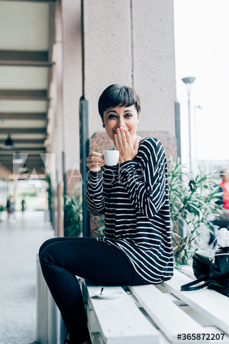 Portrait of smiling young woman drinking coffee outdoors