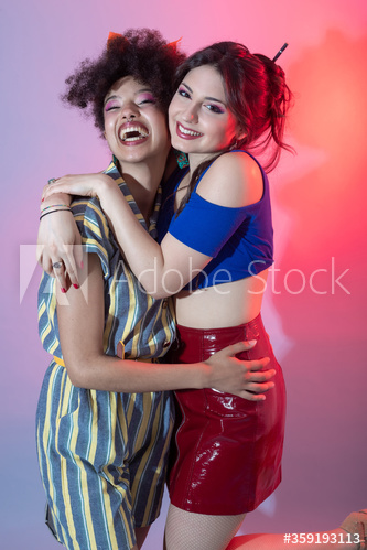 Portrait of smiling young women hugging each other indoors