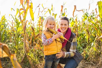 Portrait of woman and child biting kennel on farm