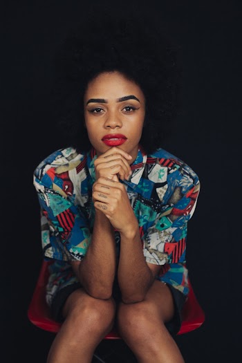 Portrait of Woman Wearing Multicolored Button-up Shirt Sitting on Red Chair