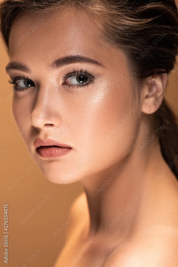portrait of young beautiful naked woman with shiny makeup isolated on beige