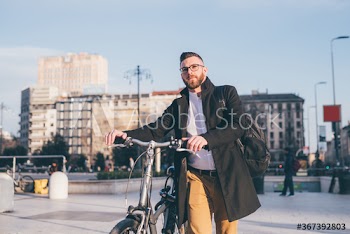 Portrait of young man with bicycle walking on street