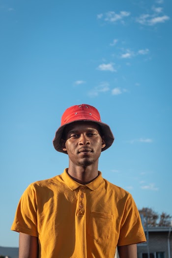 Portrait photo of a man wearing red hat and an orange polo shirt