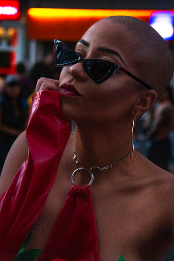 Portrait photo of a woman with a shaved head wearing black sunglasses
