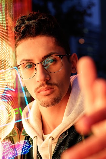 Portrait Photo of Man in Eyeglasses Leaning on Glass Window With His Hand Reached Out