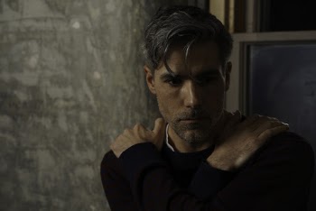 Portrait Photo of Man With His Hands Crossed Against His Shoulders Looking Away