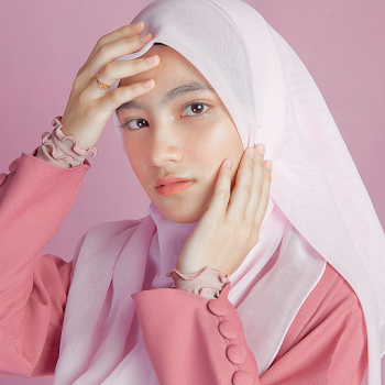 Portrait Photo of Muslim Woman in White Hijab and Pink Outfit Posing With Her Hands on Her Face Against Pink Background