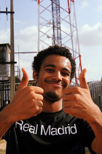 Portrait Photo of Smiling Man in Black Real Madrid Printed T-Shirt Posing With His Thumbs Up 