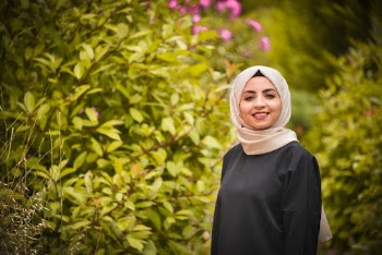 Portrait Photo of Smiling Woman in Hijab Standing Near Bushes