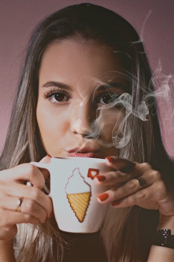 Portrait Photo of Woman Blowing on Steaming Ceramic Cup with Hot Beverage