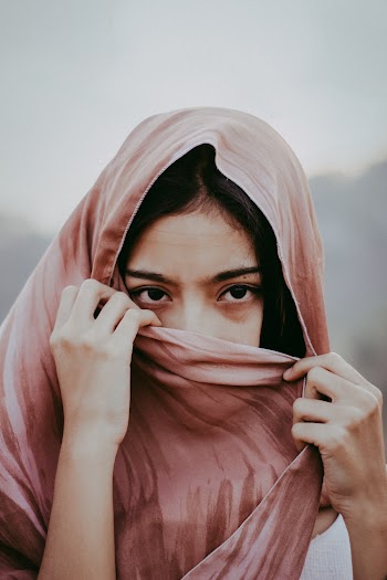 Portrait Photo of Woman Covering Her Mouth with Brown Scarf