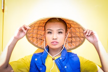 Portrait Photo of Woman in Bamboo Hat Posing In Front Of Yellow Door