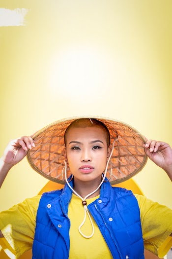 Portrait Photo of Woman in Bamboo Hat Posing In Front Of Yellow Wall
