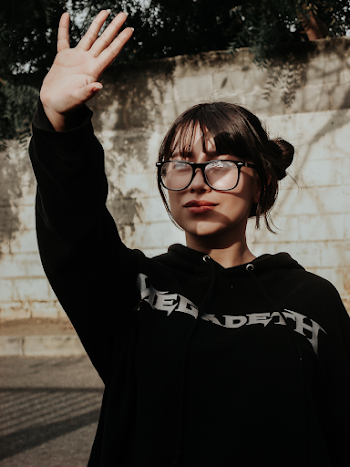 Portrait Photo of Woman in Black Hoodie Blocking the Sun with Her Hand