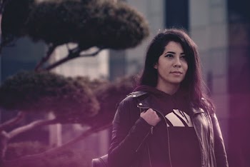 Portrait Photo of Woman in Black Leather Jacket and Hoodie Carrying a Backpack