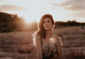 Portrait Photo of Woman in Floral Dress Posing in Grass Field During Golden Hour