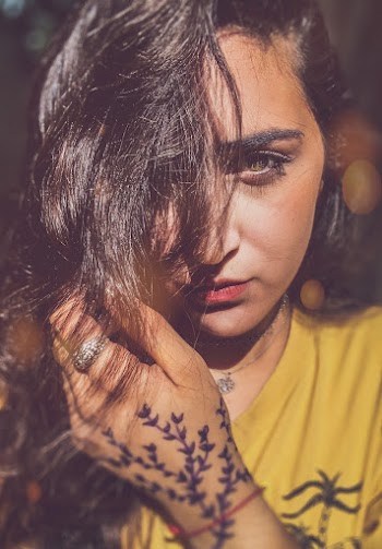 Portrait Photo of Woman in Mustard T-shirt Posing With Her Hair Covering Part of Her Face