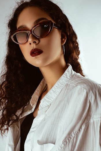 Portrait Photo of Woman in Sunglasses and Red Lipstick Posing In Front of White Background
