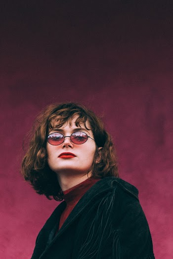 Portrait Photo of Woman in Sunglasses Posing In Front of Purple Background