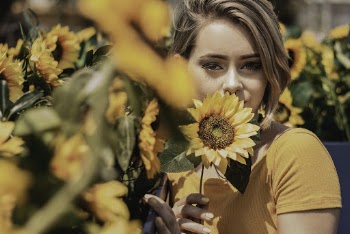 Portrait Photo of Woman in Yellow Top Posing Near Sunflowers