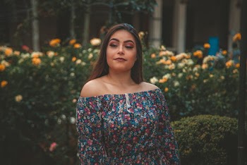 Portrait Photo of Woman Standing In Front Of Flower Hedge