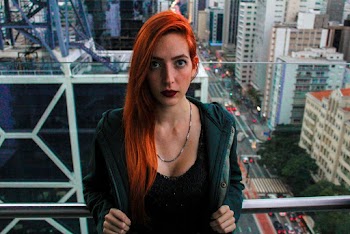 Portrait Photo of Woman Standing in Front of Glass Wall With  Cityscape in the Background