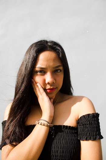 Portrait Photo of Woman Wearing Black Off-shoulder Top Holding Her Chin