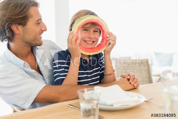 Portrait playful boy with watermelon ring at table