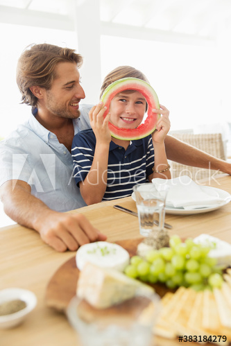 Portrait playful boy with watermelon ring at table