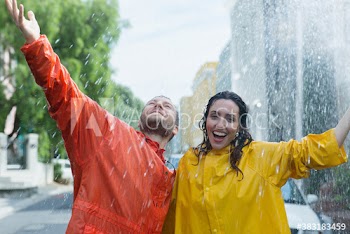 Portrait playful couple on rainy city street