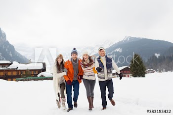 Portrait playful couples friends in snowy field outside lodge