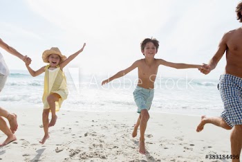 Portrait playful family running on sunny ocean beach