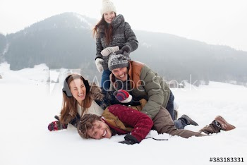 Portrait playful friends laying in snowy field