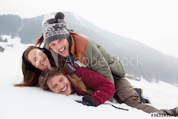 Portrait playful friends laying in snowy field
