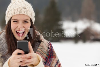 Portrait playful happy young woman with smart phone in snow