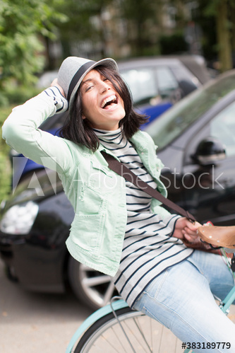 Portrait playful young woman riding bicycle on street