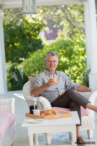 Portrait senior man enjoying breakfast and newspaper on patio