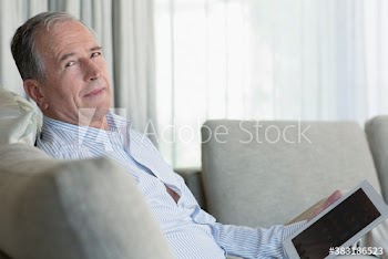 Portrait senior man using digital tablet on sofa