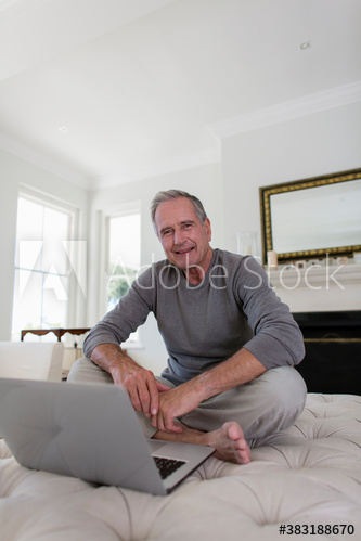 Portrait senior man using laptop on ottoman