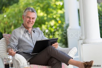 Portrait senior man using laptop on patio