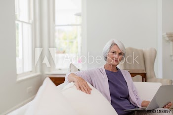 Portrait senior woman with laptop on sofa
