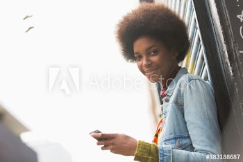 Portrait smiling beautiful young woman with afro using smart phone