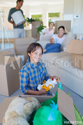 Portrait smiling boy unpacking toys in new house